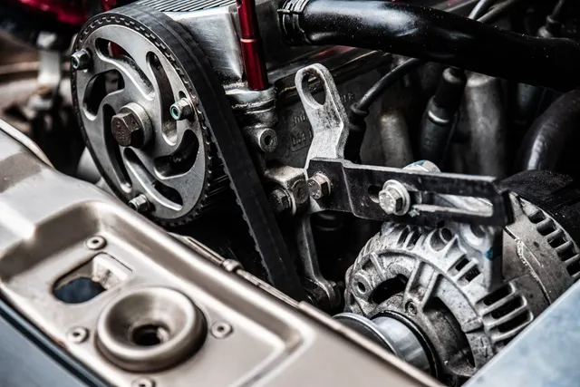 An alternator and drive belt in a vehicle engine bay