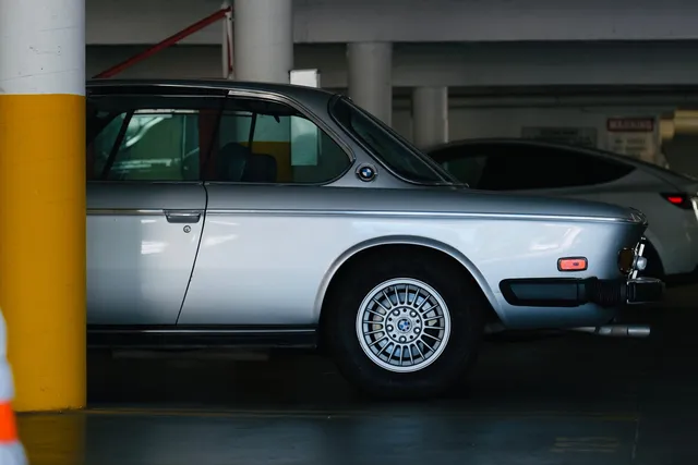 A silver classic BMW parked under cover