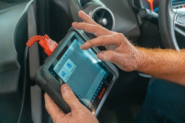 A handheld diagnostic scan tool held in both hands