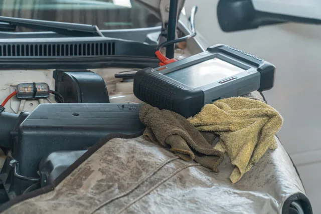 A diagnostic scan tool resting on an engine during testing