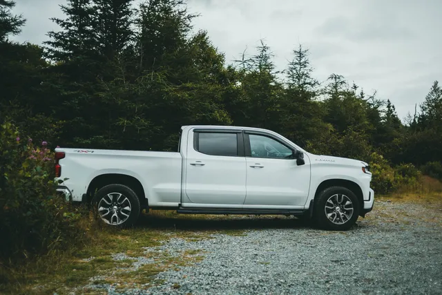 A white Chevrolet Silverado pickup beside a forest