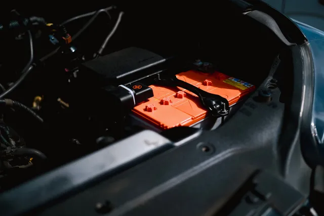 An orange high voltage component mounted in an engine bay