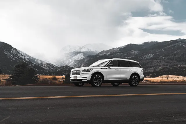 A white Lincoln SUV with mountains behind it