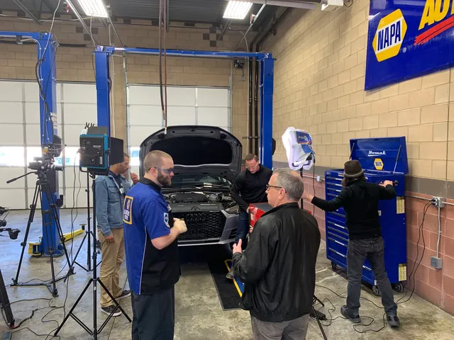 Camera crew filming a technician working on a vehicle at McNeil’s Auto Care
