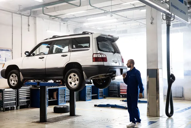 A vehicle raised on a two post lift in a workshop