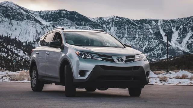A white Toyota RAV4 with mountains behind it